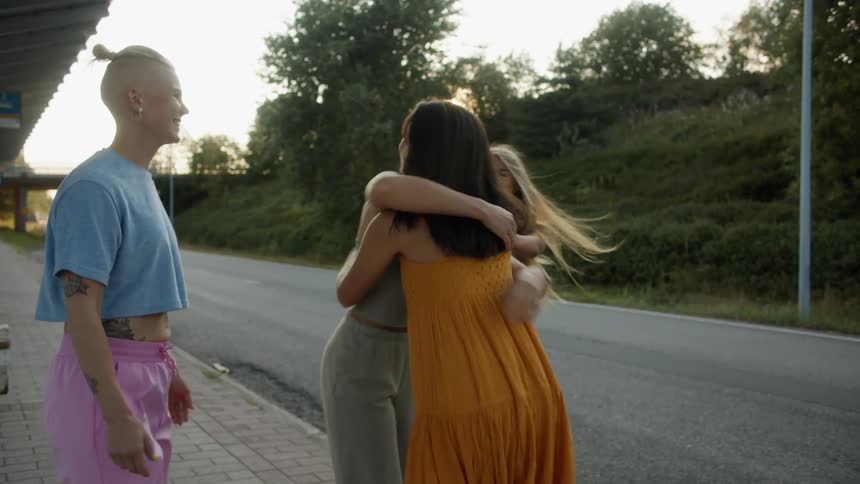 A woman is greeted by three friends on the sidewalk