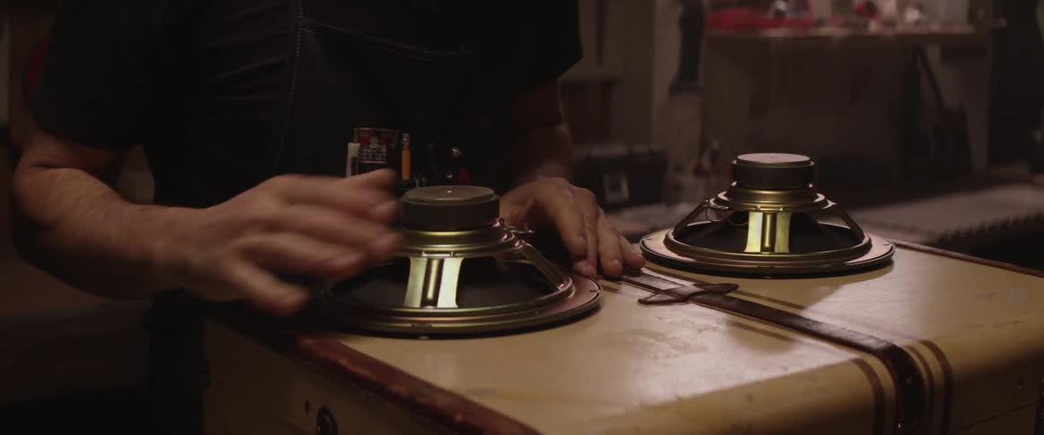 A man places a speaker on a suitcase