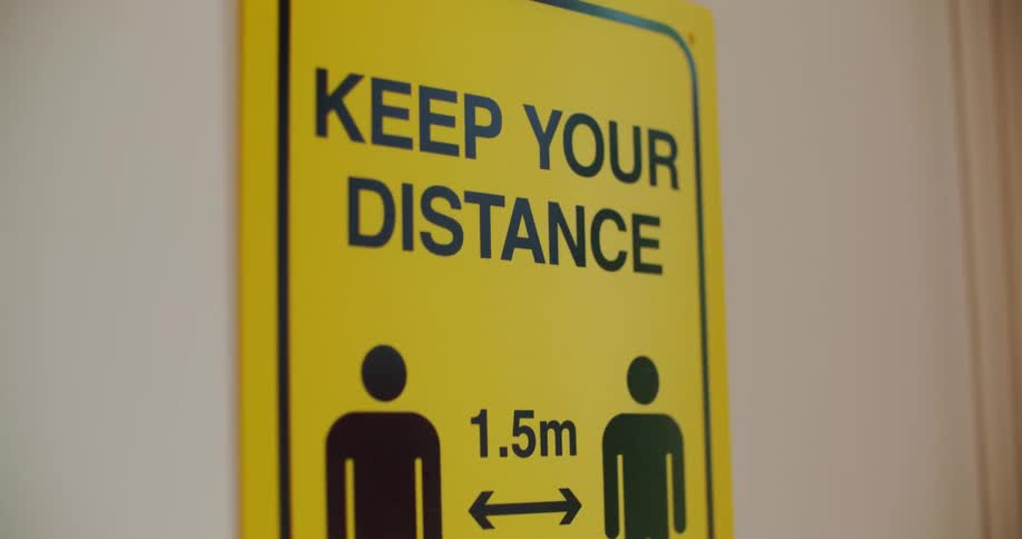A sign telling people to stay 1.5 meters apart hangs on a wall