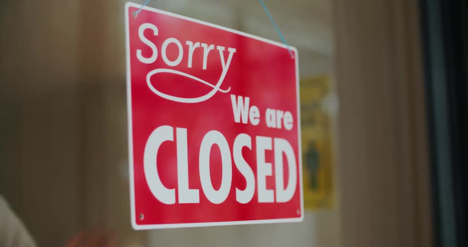 A person flipping a sign on a glass storefront