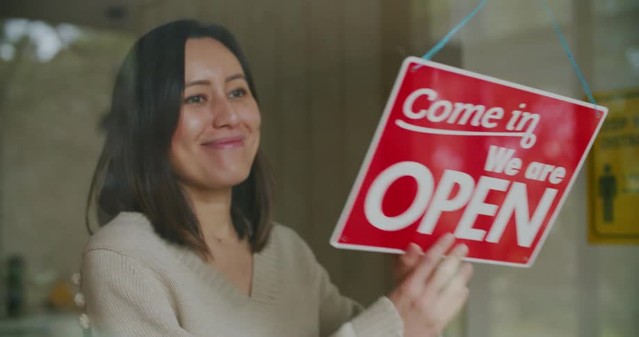 As she turns the sign to open a woman smiles very big