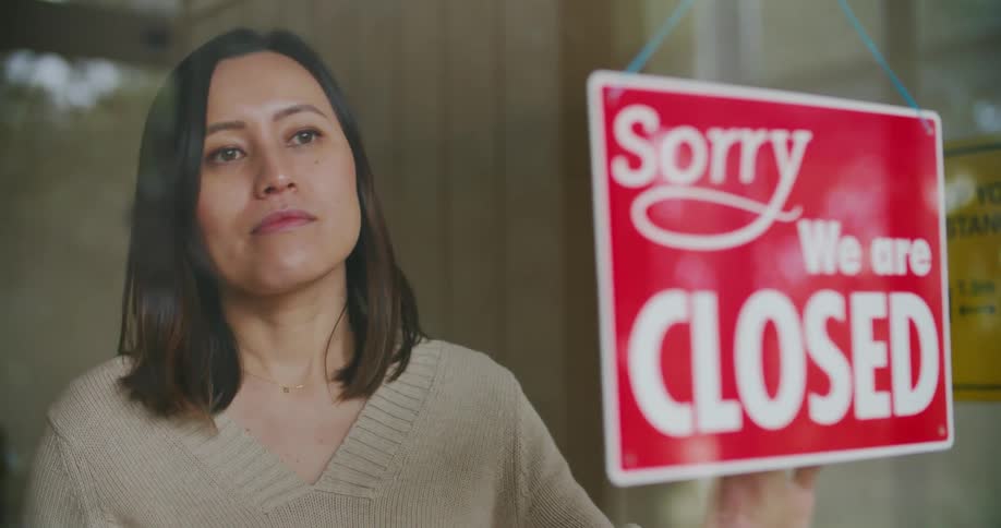 A woman flipping a sign on a glass storefront