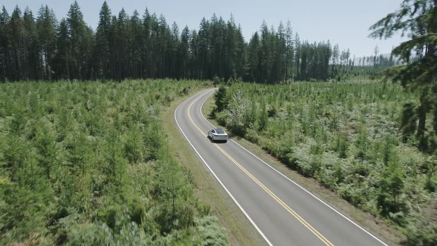 A white car drives down a country road