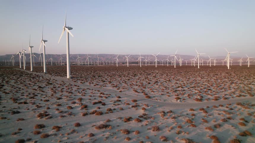 A huge field of windmills spans across the desert as they spin in the wind