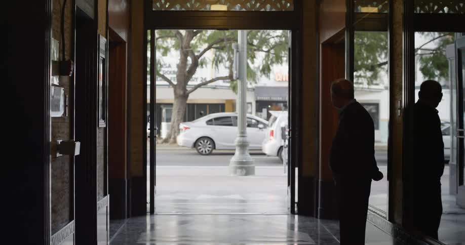 A man is standing just inside a building with the doors open to the street