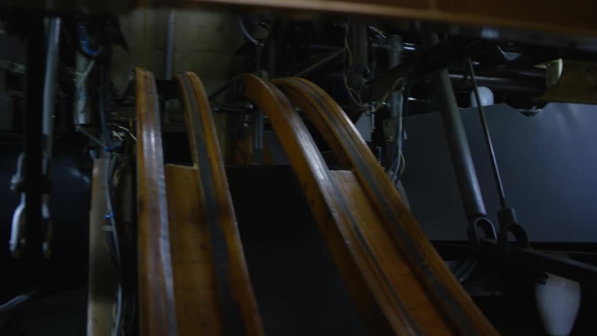 A bowling ball rolls down the bowling alley and knocks down pins and they reset as the ball rolls back down the rails