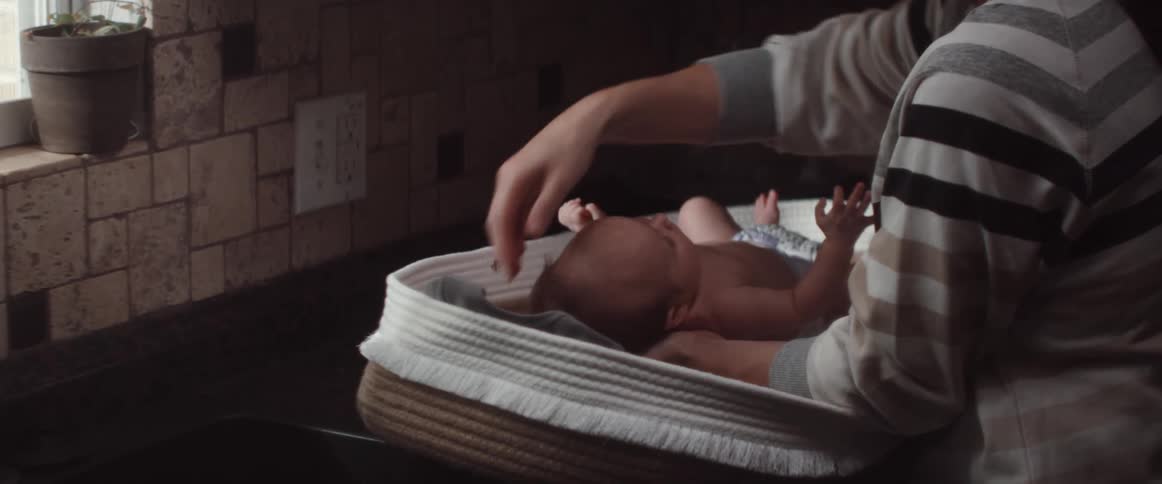 A woman lies her newborn baby in a basinet