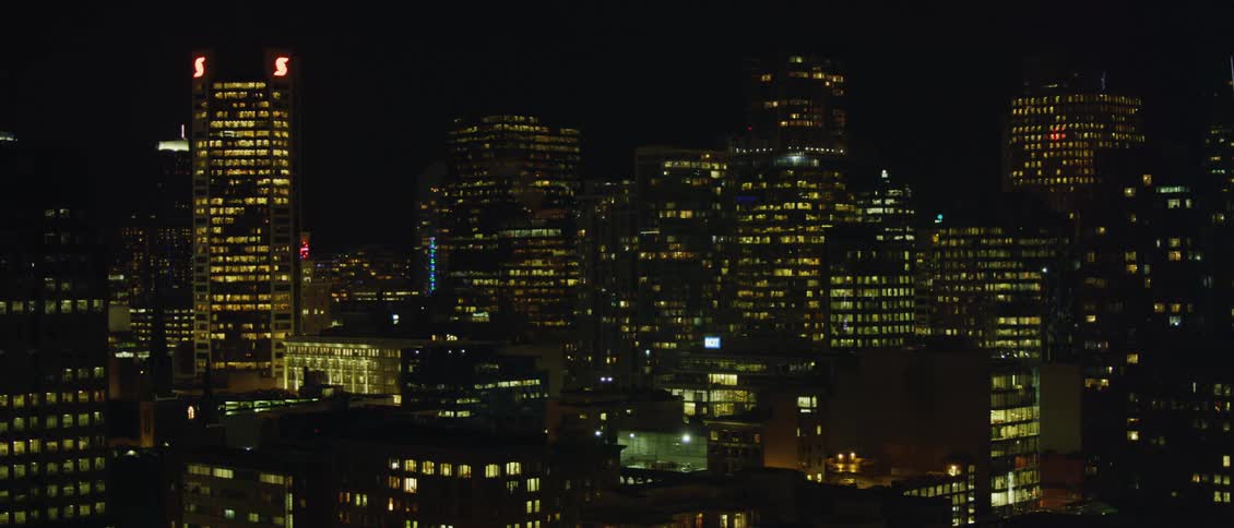 Interior lights and neon signs light up a city full of skyscrapers at night