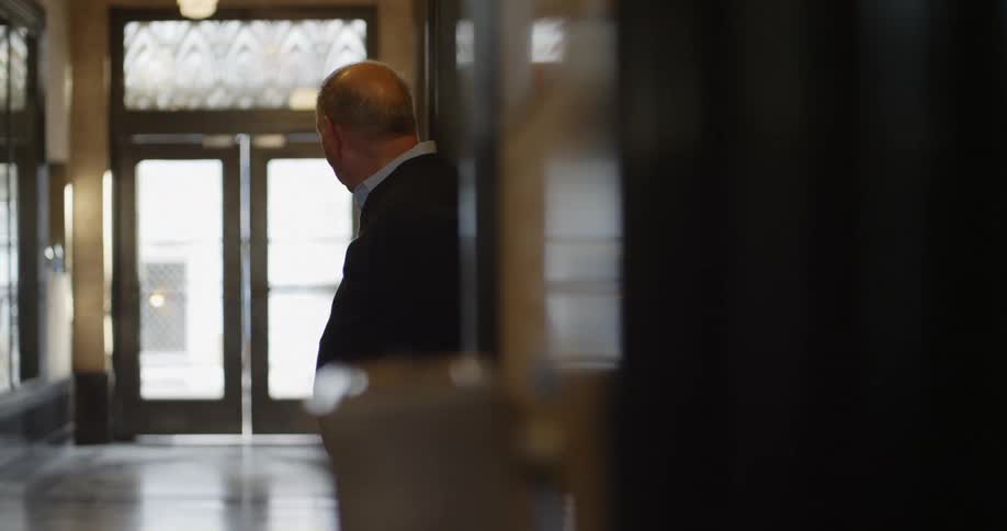 A man in a hallway with a wall and doors in the background