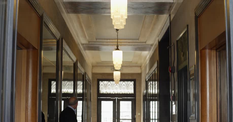 A man stands in the hallway of a building with ornate walls