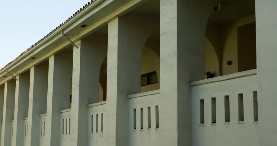 A covered walkway features arches and slot openings in the half wall