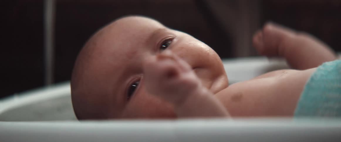 A newborn baby wrapped in a towel moves his head around
