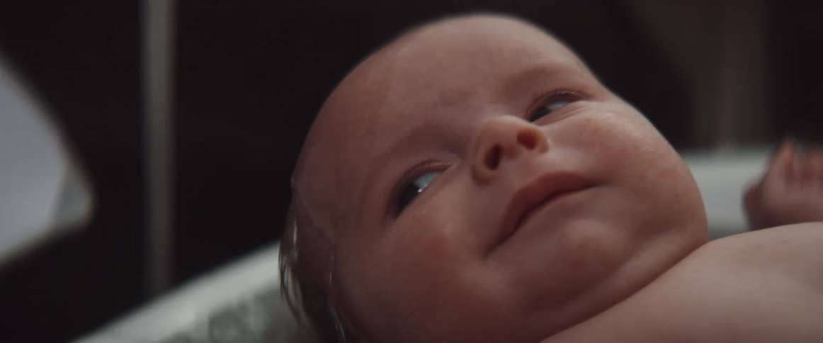 A baby has water poured on him in the bath
