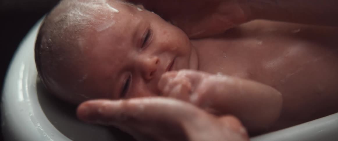 Woman gives baby crying bath in tub