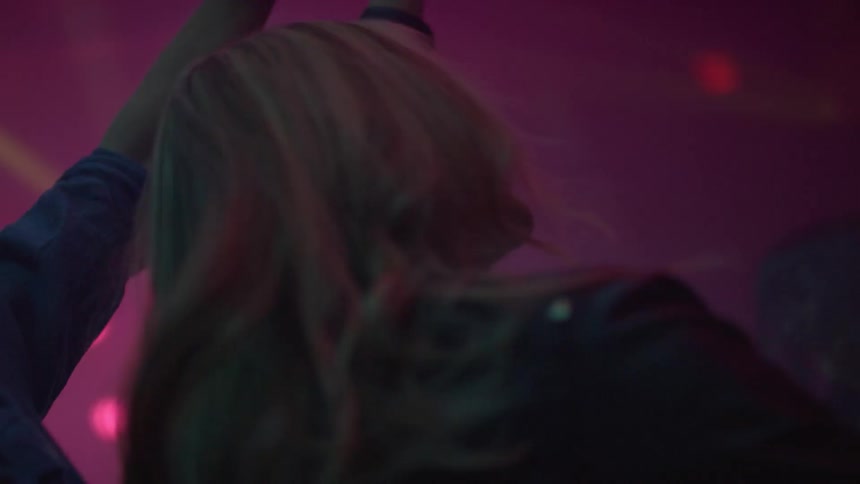 Happy blond woman dancing on a crowd inside a night club