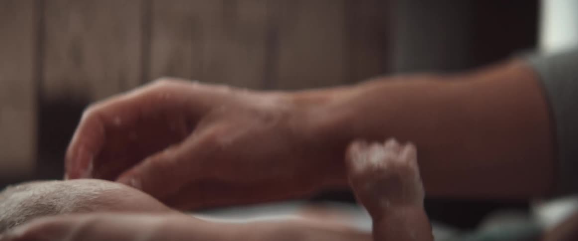 A man scrubs soap on his infants head during a bath