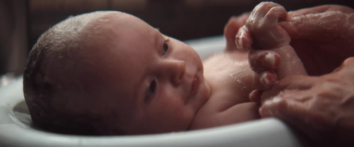 Woman gives baby bath rubbing his body