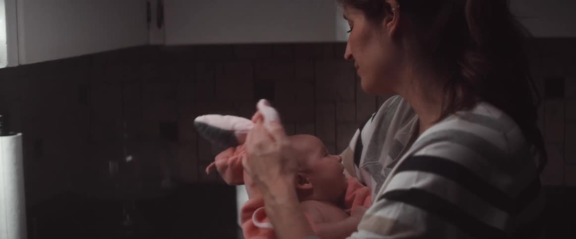 A woman in a room holding a baby with a wall in the background