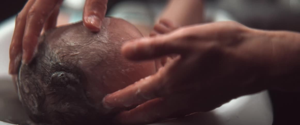 A baby is being washed in a bath with soap