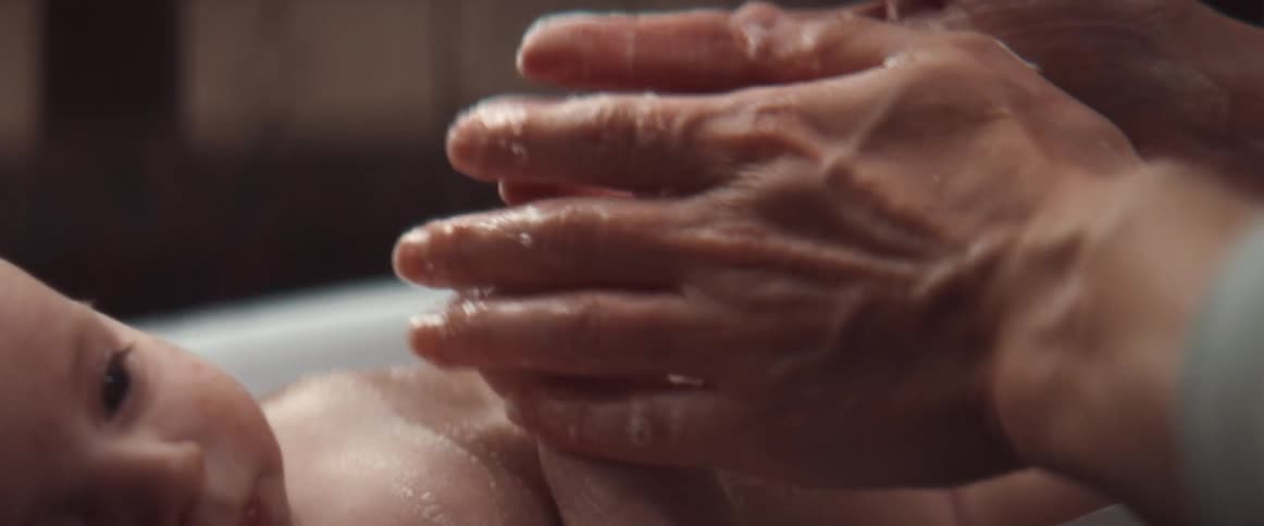 Someone is washing a baby in a small tub