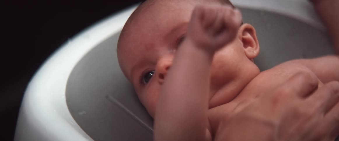 Mother giving her son a bath on a portable baby bathtub