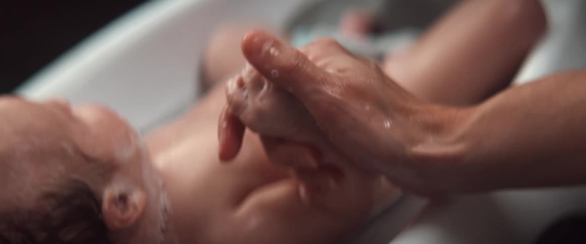 Woman gives baby bath holding her hand