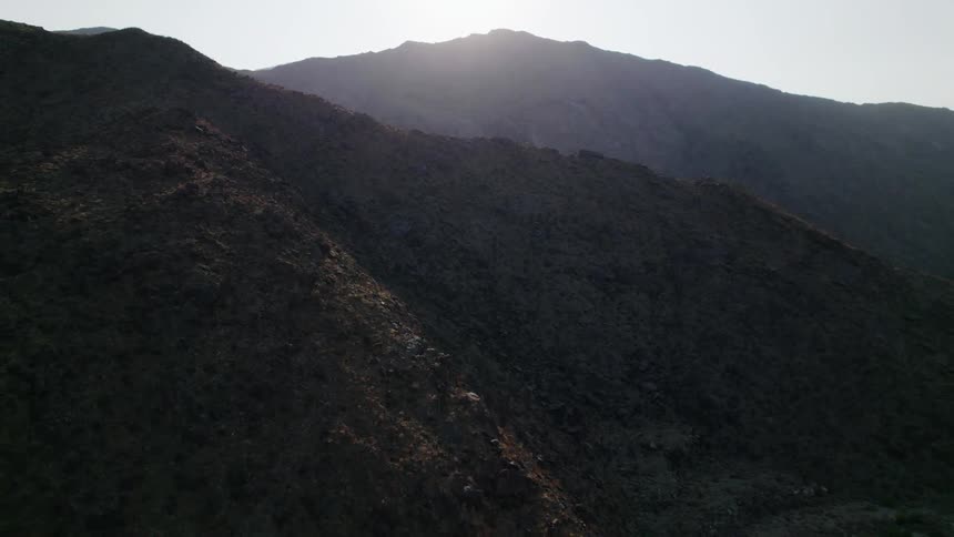 Mountain side community under a hazy sky and mountains in the distance