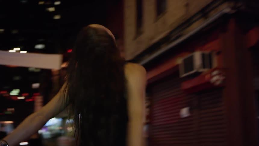 A woman is dancing in the street at night