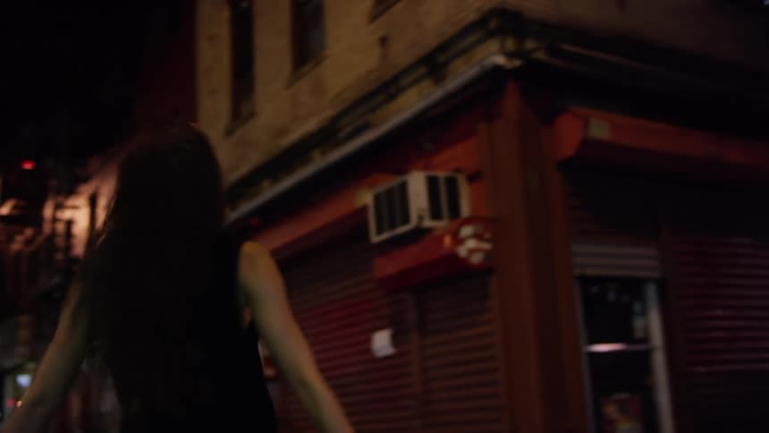 Young happy long haired woman spinning on the street of the city at night