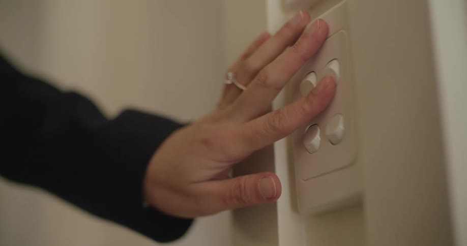 Woman wearing diamond ring adjusts wall switch