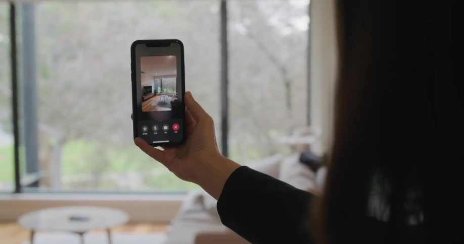 A person in a room using a smart phone with a wall and window in the background