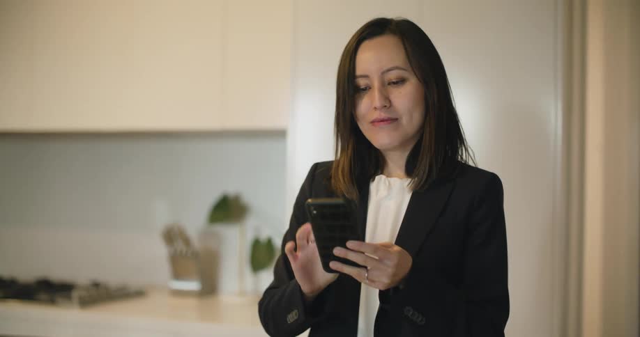 A woman sets her keys and a binder on her counter and places a video call on her phone