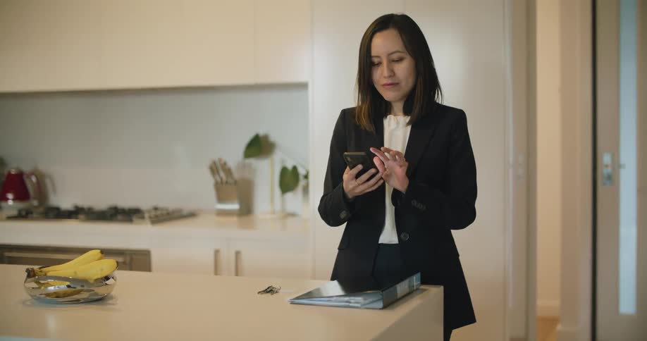 Young woman enters a room and picks up her smartphone to star a video call