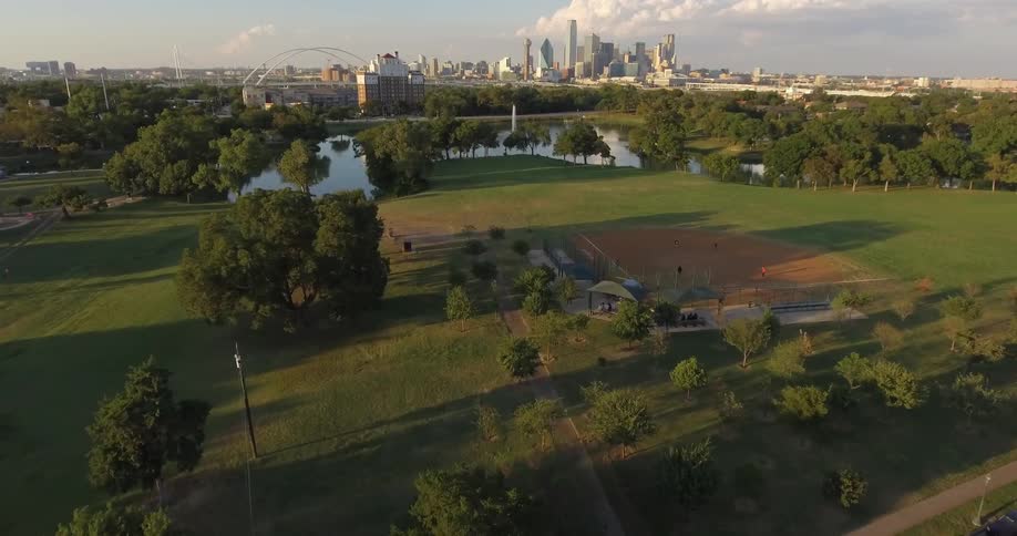 Skyscrapers stand in the distance, just belong a park and lake