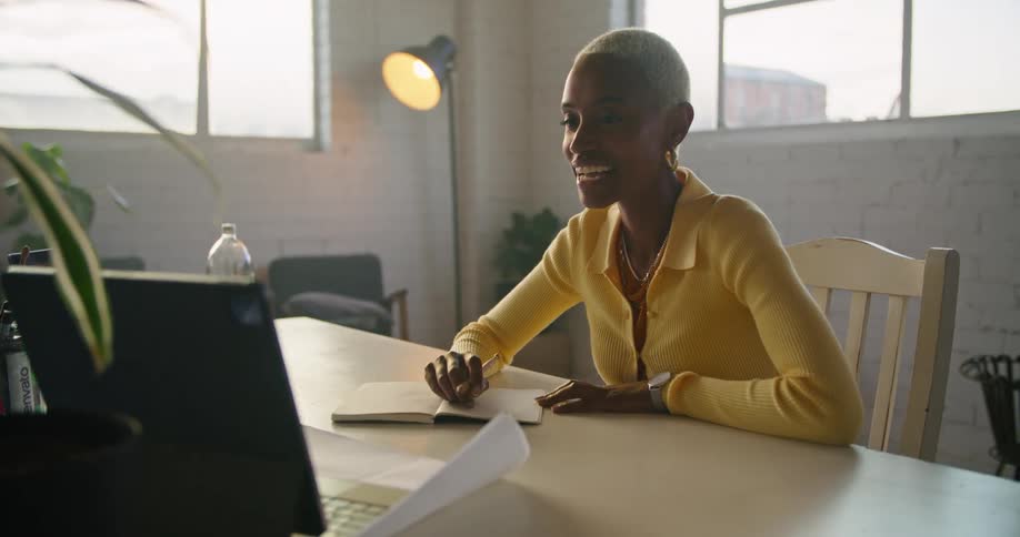 A woman smiles and nods as she talks during a zoom meeting on a laptop
