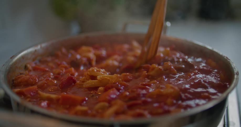 Person opens a lid of the pot and stirs boiling food