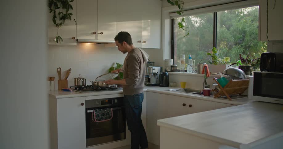 A man puts his phone away to taste food he is cooking
