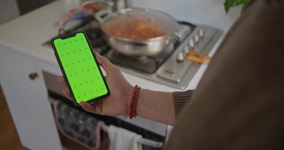 A person is holding a cellphone in the kitchen