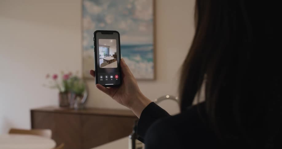 A woman participating in a video chat with her smartphone taps the screen to switch to her phones rear camera