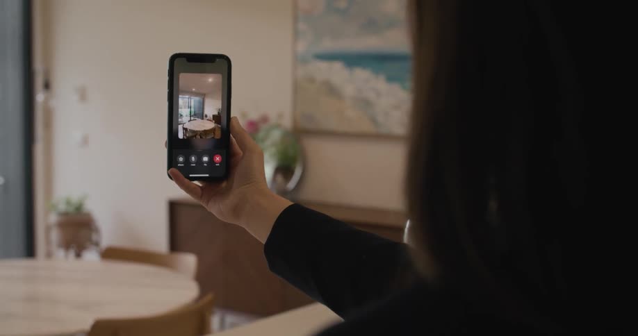 A woman is taking video of a kitchen in a home