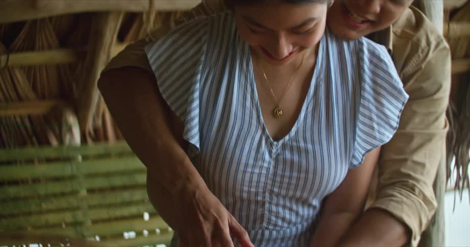 A man helps a woman cut a vegetable