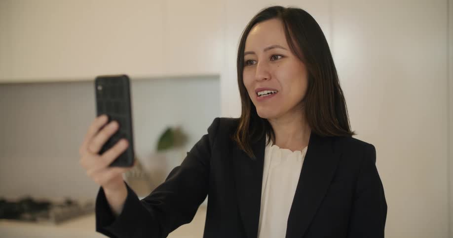 A woman is video chatting using her smartphone while indoors during the day