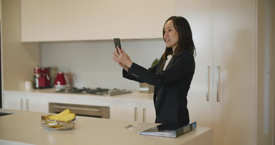 A female real estate agent takes video of a kitchen using her phone