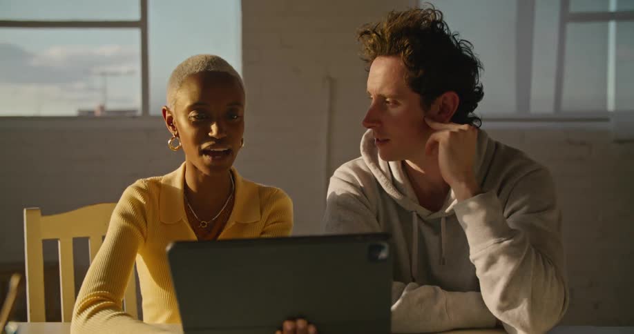 A man and woman talk and look at a tablet together