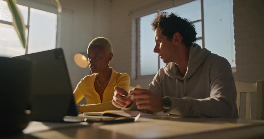 A man and woman are looking at a laptop and having a discussion