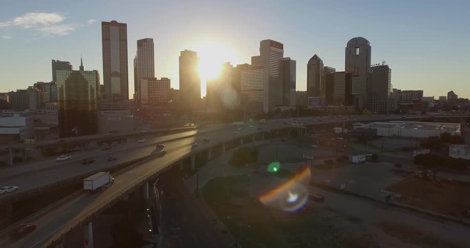 The sun rises behind a busy city