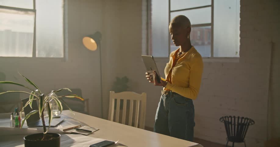 A woman is using a tablet while standing at her desk