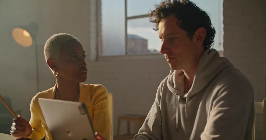 Co workers working at the office talking while looking at a laptop
