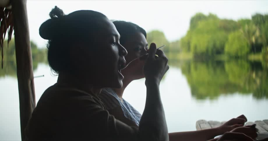 A man and woman are sitting at a table in front of a lake and eating a meal
