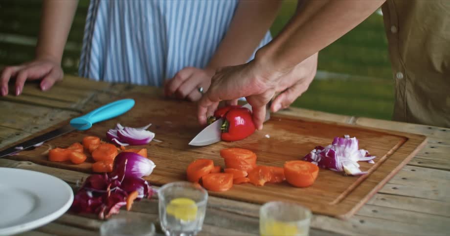 A person cutting a pepper with a knife on a cutting board